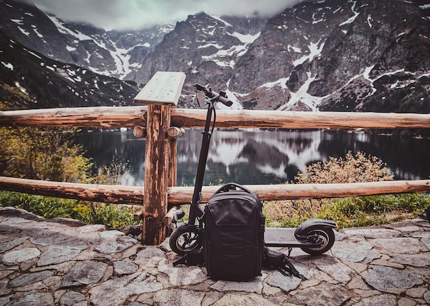 Punto de vista turístico con una vista increíble de las montañas y el lago con reflejo espejado. Trere son scooter en la parte delantera.