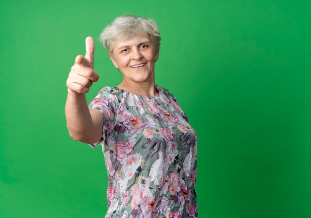 Puntos de anciana sonriente aislados en la pared verde