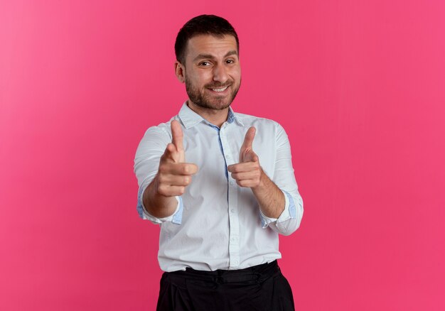 Puntos de hombre guapo sonriente con dos manos aisladas en la pared rosa