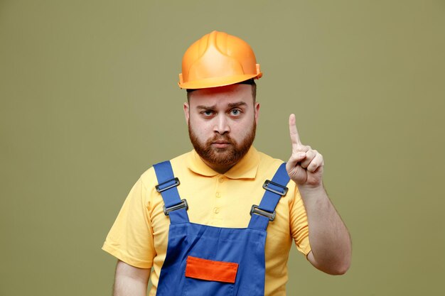 Puntos impresionados en el hombre joven constructor en uniforme aislado sobre fondo verde