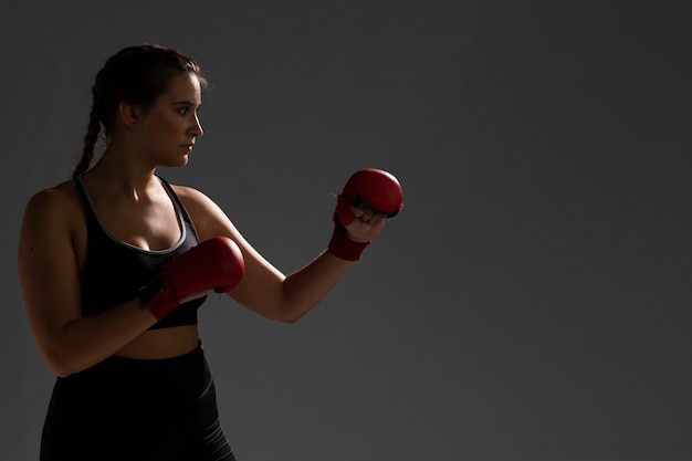 Foto gratuita punzonado con guantes de box y fondo oscuro