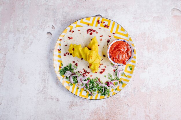 Puré de papas con salsa de tomate, cebolla y hierbas dentro del plato.