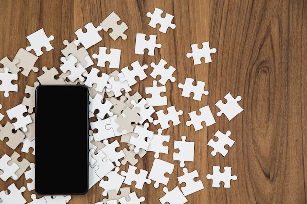 Puzzle de piezas y smartphone en mesa de madera.