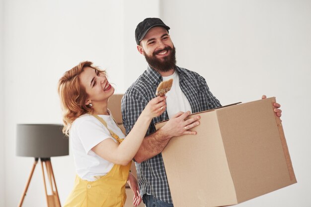 ¿Qué tipo de color quieres en esa pared? Pareja feliz juntos en su nueva casa. Concepción de mudanza