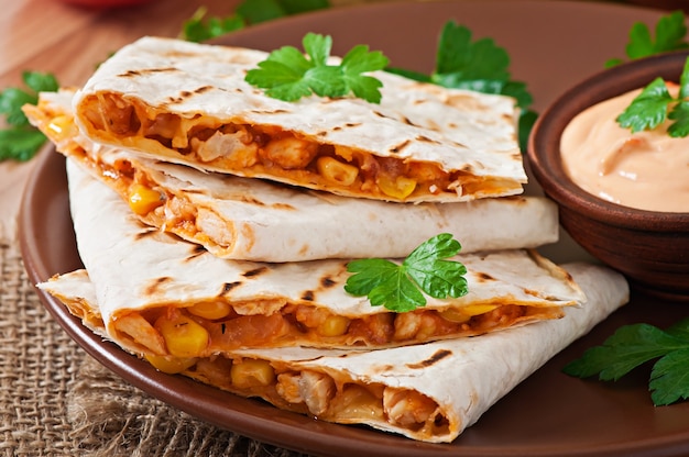 Quesadilla mexicana en rodajas con verduras y salsas sobre la mesa