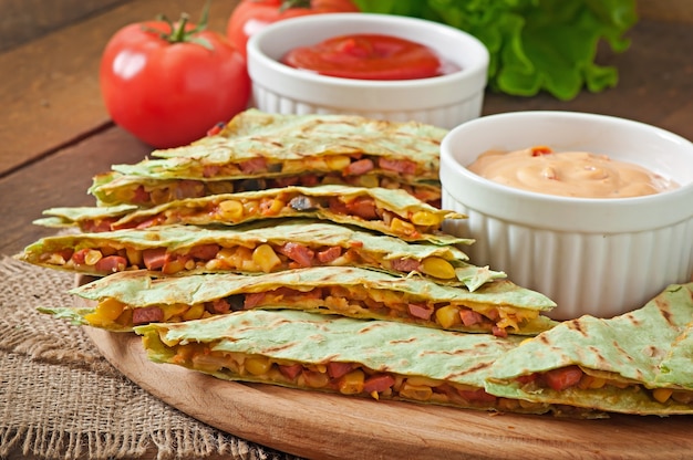 Quesadilla mexicana en rodajas con verduras y salsas sobre la mesa