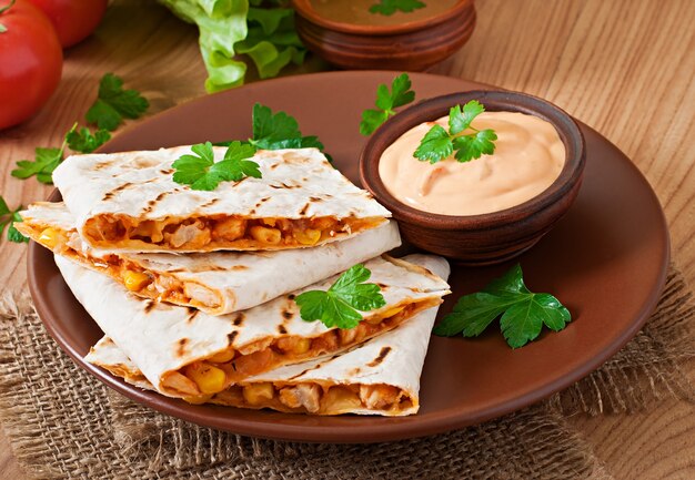 Quesadilla mexicana en rodajas con verduras y salsas sobre la mesa