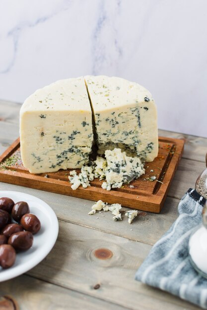 Queso azul con aceitunas en mesa de madera