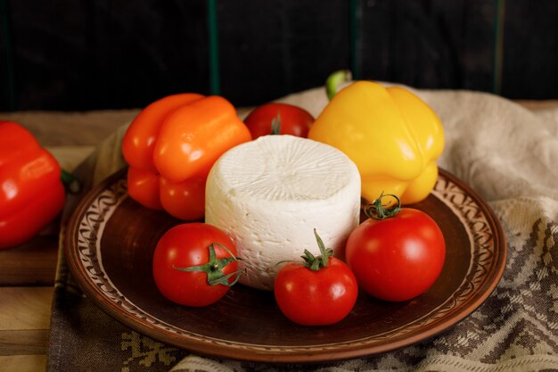 Queso blanco servido con tomates y pimientos de colores.