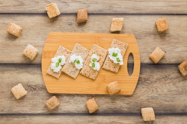 Queso crema fresco en pan crujiente sobre la tabla de cortar en el escritorio