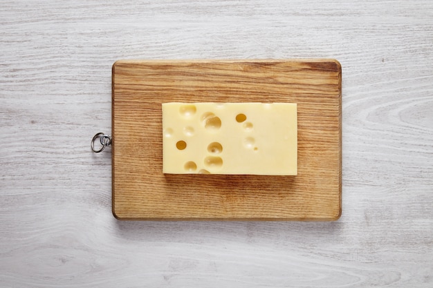 Queso emmental aislado a bordo en la mesa de la granja cepillado blanco