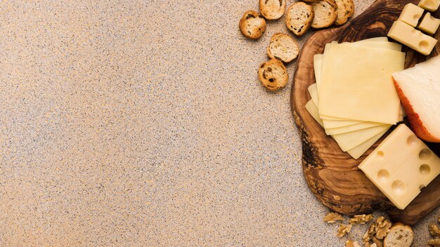 Queso Emmental y queso Gouda con rebanadas en posavasos con rebanadas de pan y nogal sobre fondo texturado beige