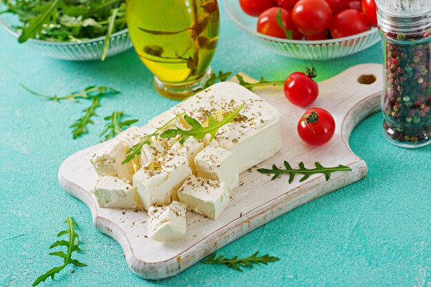 Queso feta, tomates cherry y rúcula sobre la mesa. Ingredientes para ensalada.