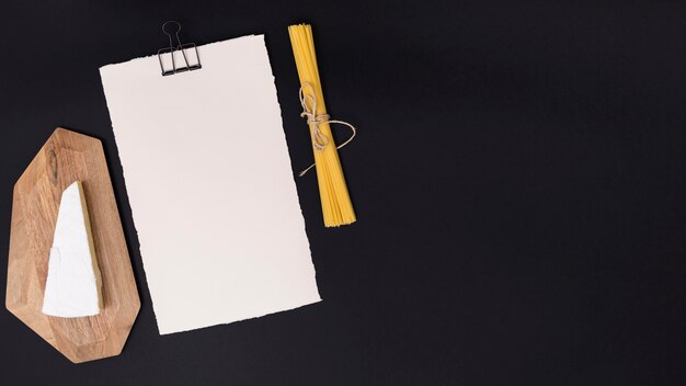 Queso; Pasta de espagueti y papel blanco en blanco sobre fondo negro