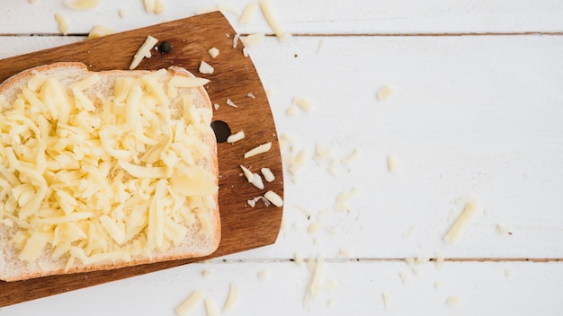 Queso rallado en pan sobre la tabla de cortar en el escritorio de madera