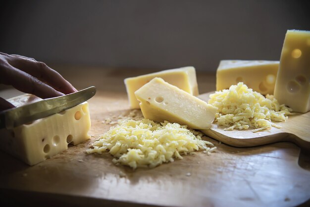 Queso de la rebanada del corte de la mujer para el cocinero usando cuchillo en la cocina - gente que hace la comida con concepto del queso