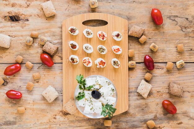 Queso en tabla para picar con tomate y pastelería en escritorio