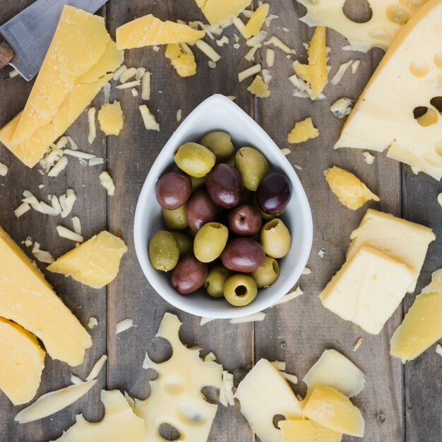 Queso untado cerca de la oliva en la mesa de madera