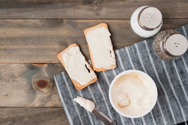 Queso para untar en el pan tostado con salero y pimentero en mesa de madera