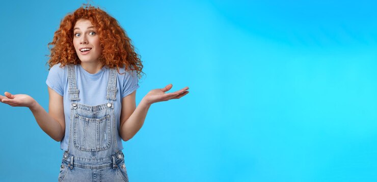 Foto gratuito quién sabe descuidado despistado atractivo juguetón pelirroja linda chica de pelo rizado encogiéndose de hombros sin darse cuenta