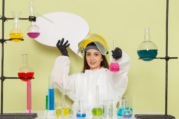 Foto gratuita química femenina de vista frontal en traje de protección especial trabajando con diferentes soluciones en la superficie verde
