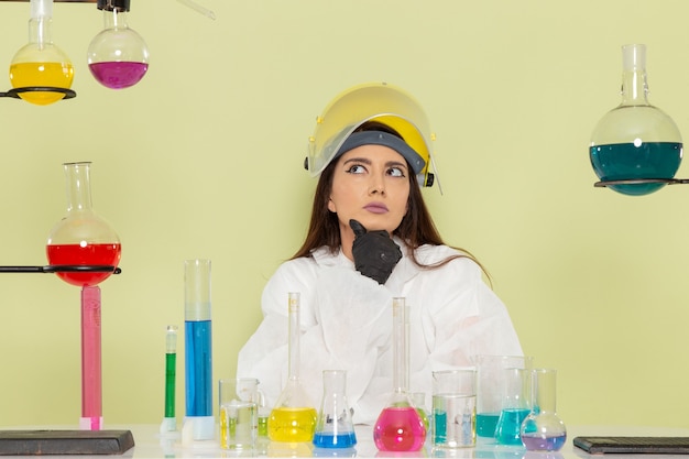 Foto gratuita químico femenino de vista frontal en traje de protección especial pensando en la superficie de color verde claro