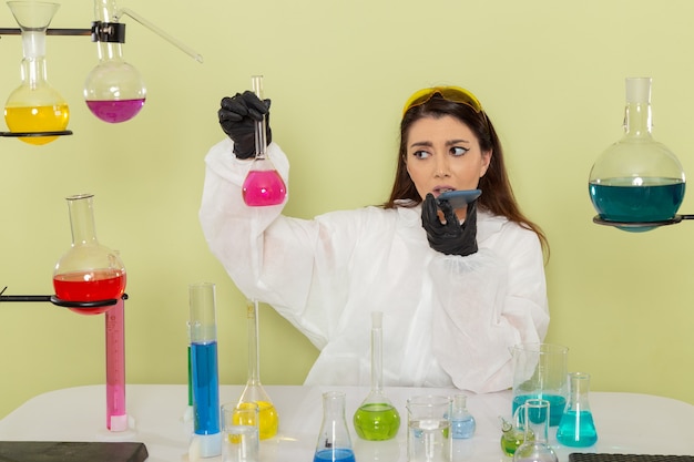 Foto gratuita químico femenino de vista frontal en traje de protección especial con solución rosa en la superficie de color verde claro