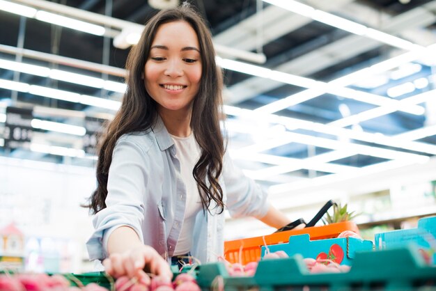 Rábano asiático sonriente de la cosecha de la mujer en mercado