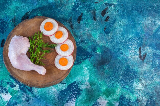 Rábano en rodajas y zanahorias con eneldo y muslo de pollo en una tabla