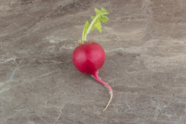 Rábano rojo con hoja sobre superficie de mármol