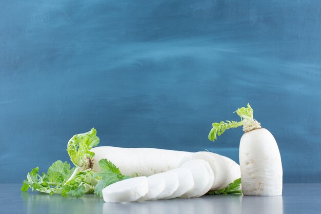 Rábanos daikon blanco en rodajas sobre mármol.