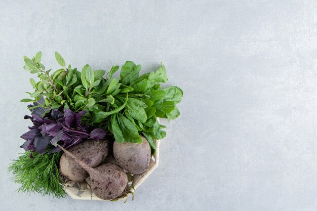 Rábanos deliciosos con verduras en un tazón, sobre el fondo de mármol.