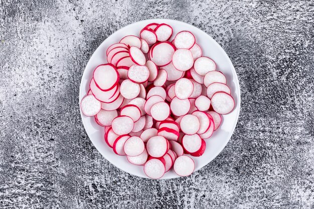 Rábanos rojos picados frescos en un plato blanco