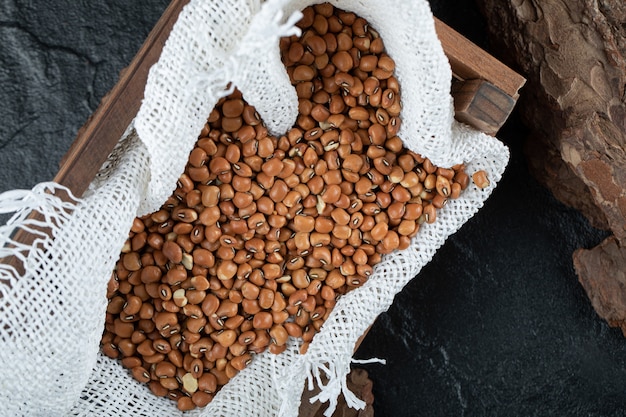 Racimo de frijoles rojos en caja de madera con arpillera.