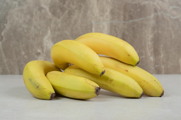 Racimo de plátanos amarillos en mesa gris