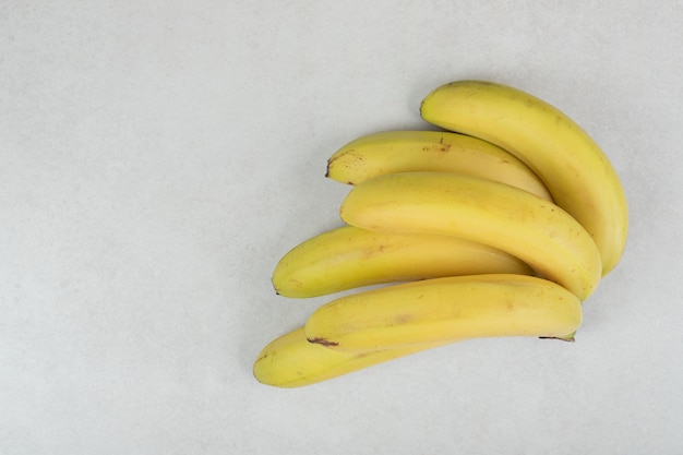 Racimo de plátanos amarillos sobre superficie gris.