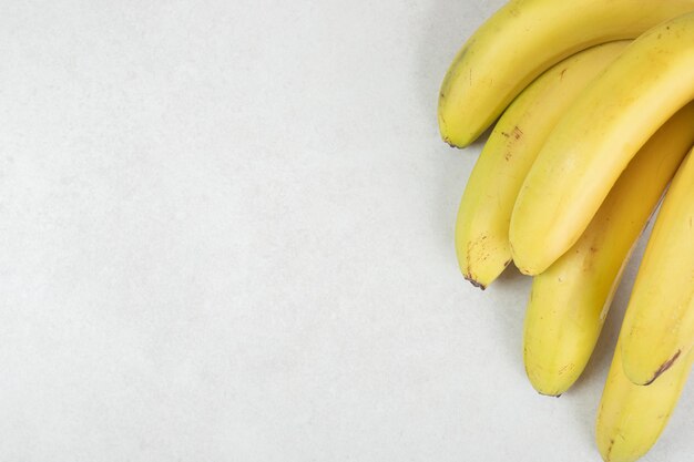 Racimo de plátanos amarillos sobre superficie gris