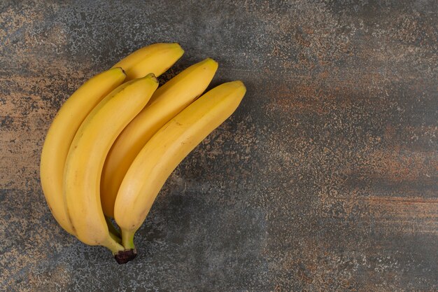 Racimo de plátanos maduros en mesa de mármol.