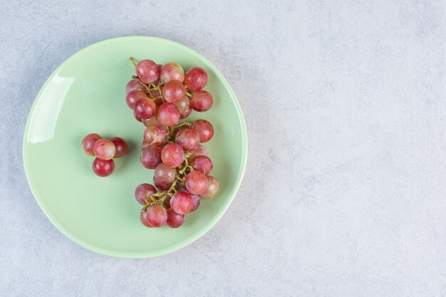 Racimo de uva orgánica fresca roja en placa verde.