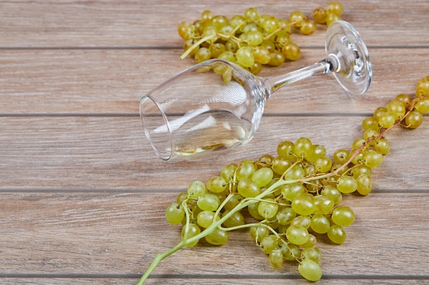 Foto gratuita un racimo de uvas y copa de vino sobre superficie de madera