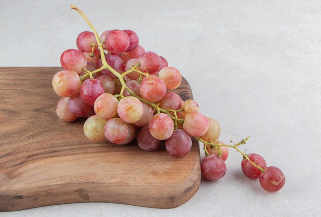 Racimo de uvas frescas sobre tabla de madera.