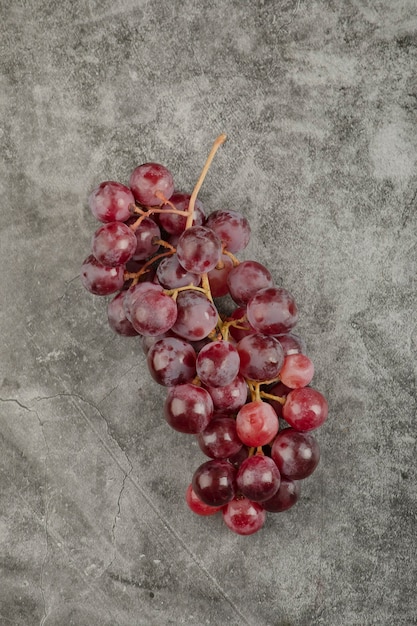 Racimo de uvas maduras frescas rojas sobre la superficie de mármol.