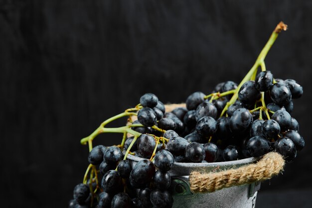 Un racimo de uvas negras en la cuchara sobre una superficie oscura