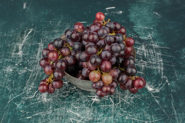 Un racimo de uvas negras en el jarrón de mesa de mármol.