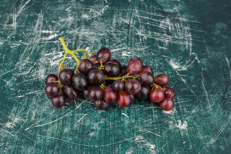 Foto gratuito un racimo de uvas negras en una mesa de mármol