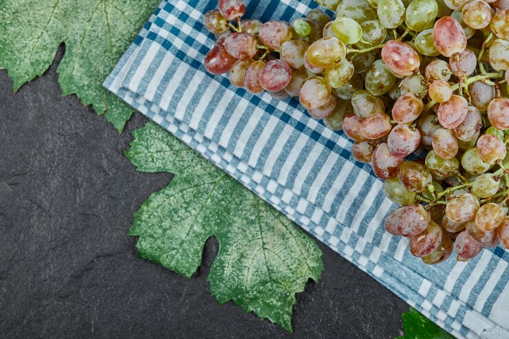 Foto gratuito un racimo de uvas rojas con hojas sobre fondo oscuro. foto de alta calidad