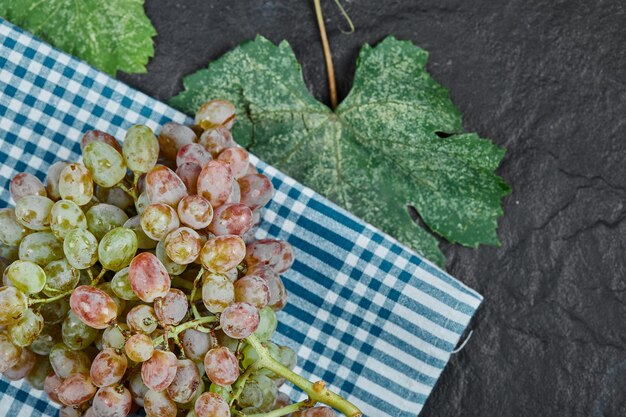 Un racimo de uvas rojas con hojas sobre fondo oscuro. Foto de alta calidad