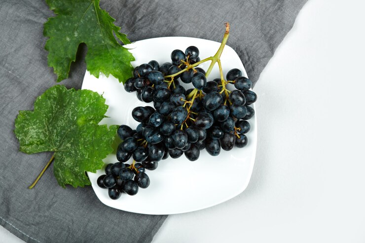 Foto gratuito un racimo de uvas rojas en un plato blanco.