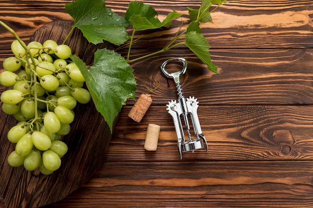 Racimo de uvas con sacacorchos sobre fondo de madera