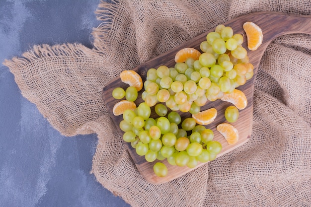 Un racimo de uvas verdes en bandeja de madera.
